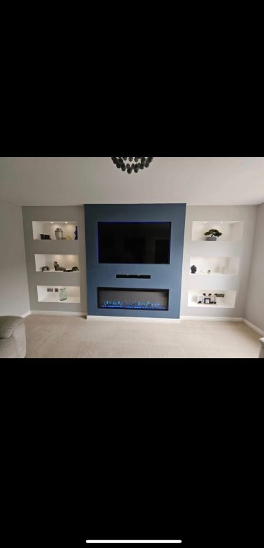 Modern living room featuring a blue feature wall, TV, and decorative shelves.